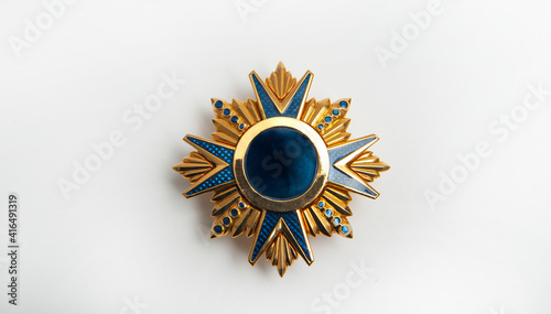 Jewelry on a dark background, yellow metal medal with blue details