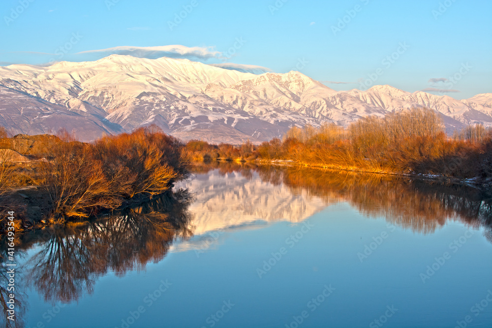 Trees around a flowing river. snowy mountains far away.A wonderful winter landscape.
