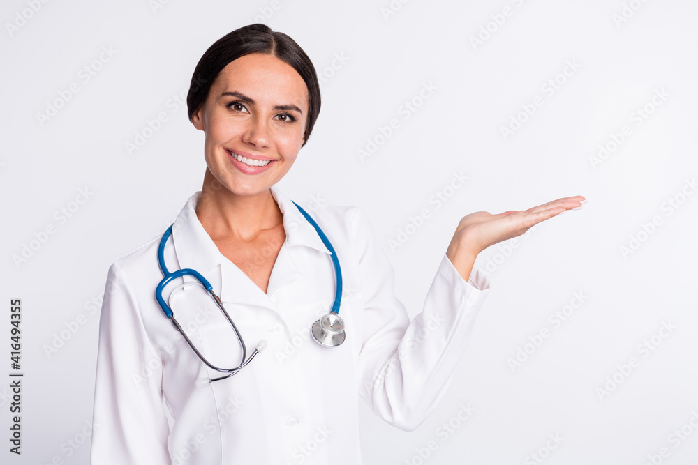 Photo of confident cheerful young woman physician wear formal coat holding arm empty space isolated white color background Photo of confident cheerful young woman physician wear formal coat holding arm empty space isolated white color background