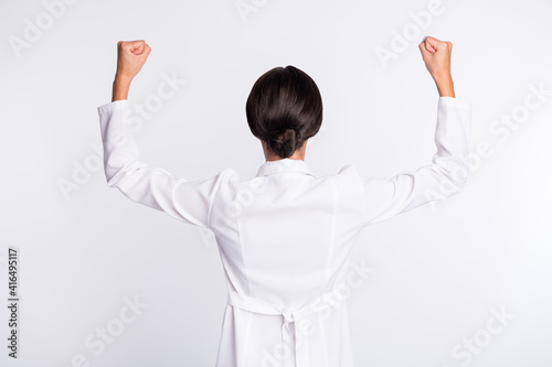 Photo of pretty slim young lady doctor back dressed uniform rising fists isolated white color background photo