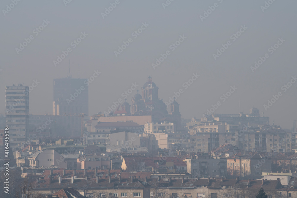 Smog lies over the skyline of Historical architecture of Belgrade city. Poor visibility, smog, caused by air pollution. Rooftop view. Emissions of plants and factories. Belgrade, Serbia 25.02.2021