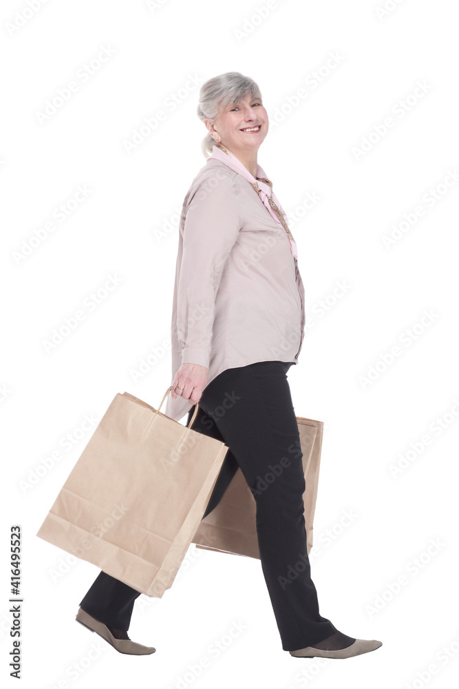 smiling old lady with shopping bags striding forward .