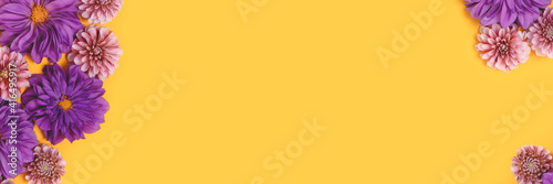 Banner with frame made of dahlia flowers on a yellow background with copyspace. Springtime creative composition.