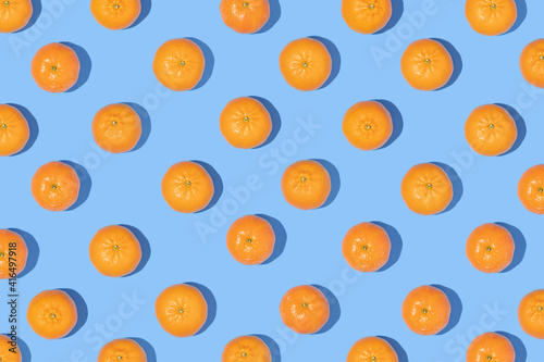 Fototapeta Naklejka Na Ścianę i Meble -  Creative pattern made with tangerines on pastel blue background. Minimal flat lay. Spring or summer aesthetic composition. Fun idea with citrus fruits.