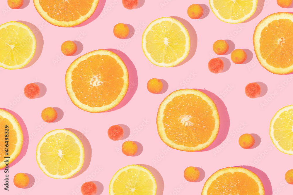 Creative pattern made with orange and lemon slices with candies on pastel pink background. Retro style aesthetic. Creative idea with citrus fruits. Flat lay composition.