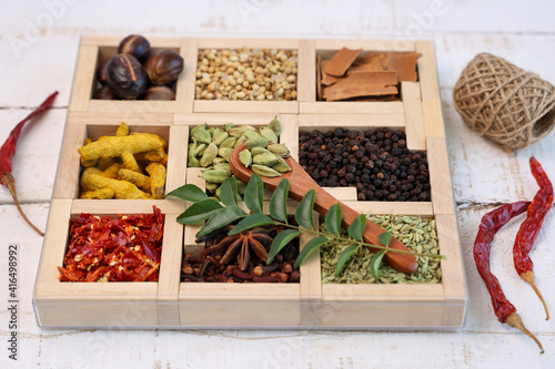 Fototapeta Naklejka Na Ścianę i Meble -  Indian spices for Indian cooking Masala hot spicy curry  whole spices turmeric, cardamom, black pepper in wooden spoon curry leaves paprika in Indian spice box Kerala India Sri Lanka.