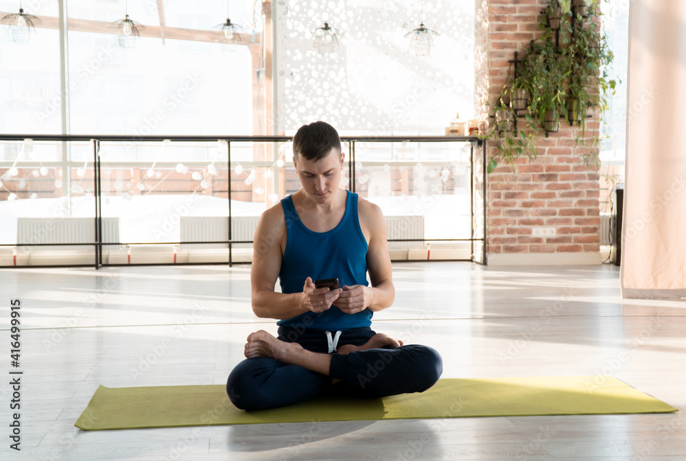 man one person doing yoga on-line holding mobile phone in hands