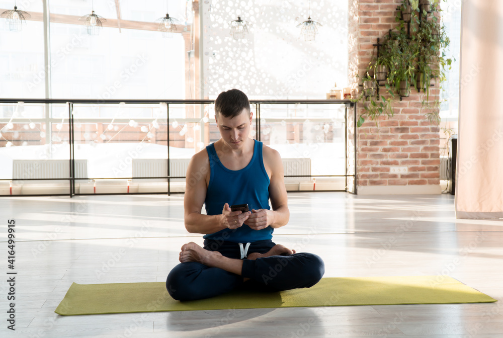 man one person doing yoga on-line holding mobile phone in hands man one person doing yoga on-line holding mobile phone in hands