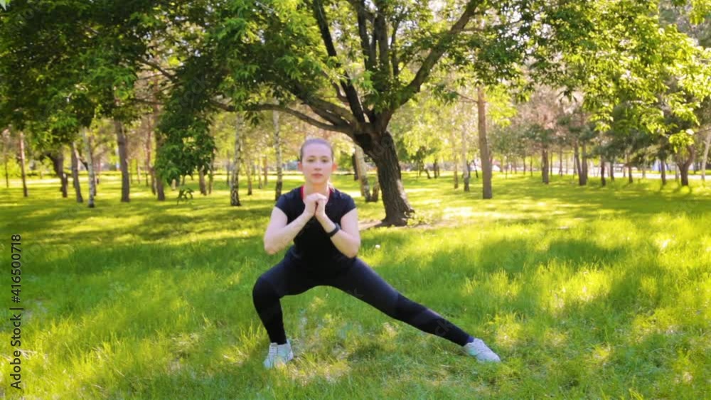 A young, slender woman in a sports uniform does a lunge exercise to train the muscles of the legs. Fitness classes in nature. A young, slender woman in a sports uniform does a lunge exercise to train the muscles of the legs. Fitness classes in nature.