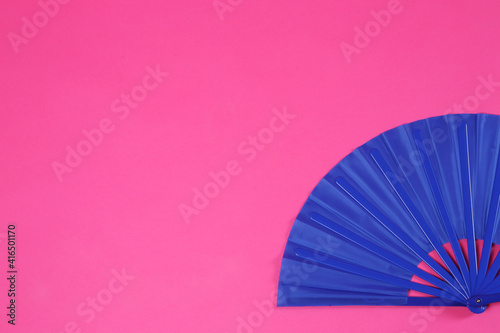 Blue hand fan on pink background  top view. Space for text