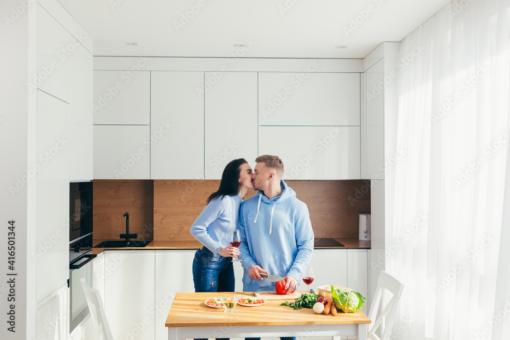 A young couple in love, a man and a woman, are cooking dinner together and having fun in a new apartment A young couple in love, a man and a woman, are cooking dinner together and having fun in a new apartment