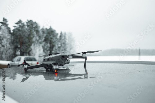 Fototapeta Naklejka Na Ścianę i Meble -  A vertical shot of a drone on the roof of a car against a blurred winter background