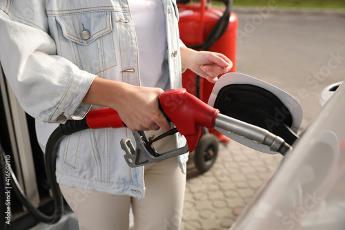 Woman refueling car at self service gas station, closeup