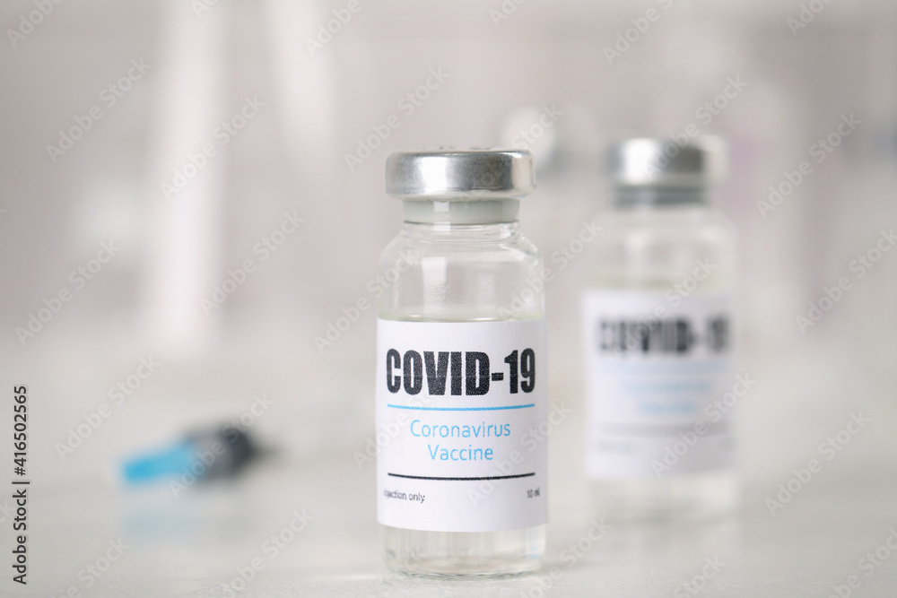 Vials and syringe with coronavirus vaccine on light table Vials and syringe with coronavirus vaccine on light table