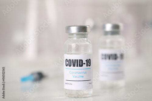 Vials and syringe with coronavirus vaccine on light table