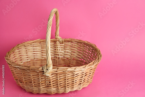 Empty wicker basket on pink background, space for text. Easter item