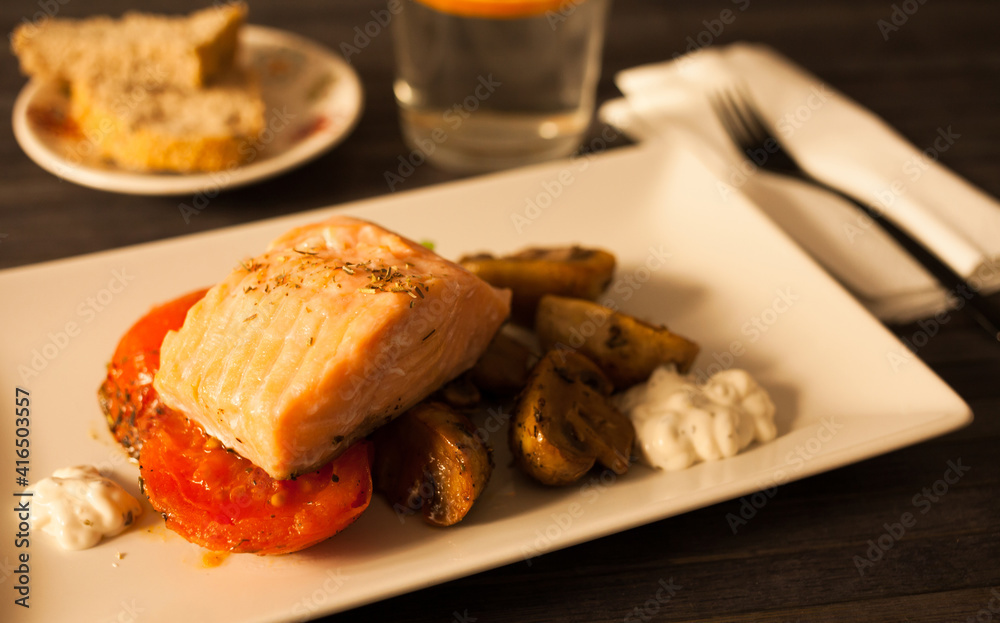 simmered slice of salmon with tomato spinon and coconut sauce on a white plate simmered slice of salmon with tomato spinon and coconut sauce on a white plate