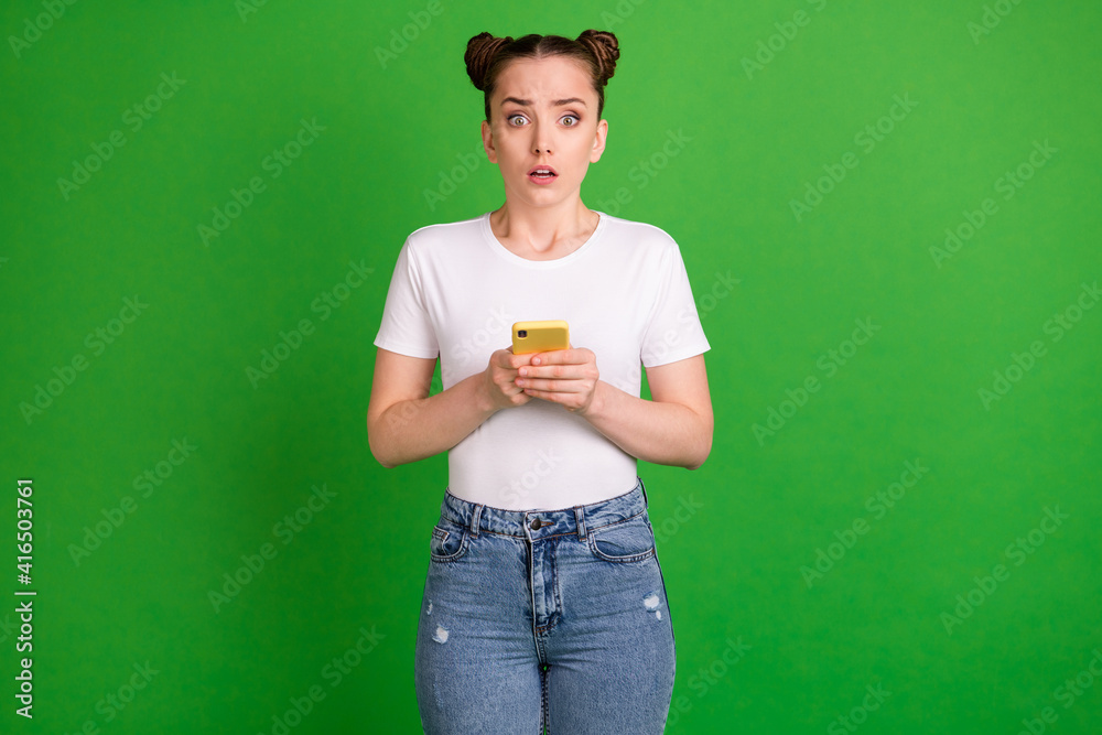 Photo of scared anxious lady hold telephone worried look camera wear white t-shirt isolated green background Photo of scared anxious lady hold telephone worried look camera wear white t-shirt isolated green background