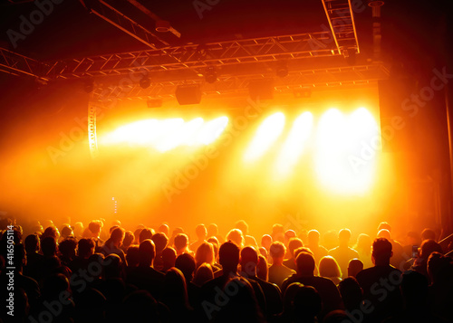 Crowd shot during a concert with stage lights and thick smoke