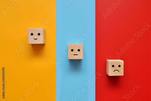 Wooden cubes with drawings of various human emotions: Sadness,  calmness, joy on multi-colored backgrounds 