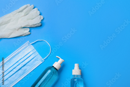 Medical gloves, mask and hand sanitizers on light blue background, flat lay. Space for text
