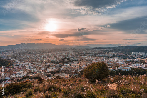 beautiful views from the top of the hill over the city of Malaga with the mountains and the cloudy sky in the background at sunset