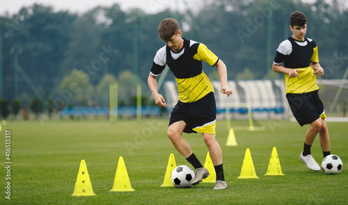 Boys on soccer football training. Young players dribble ball between training cones. Players on football practice session. Soccer summer training camp