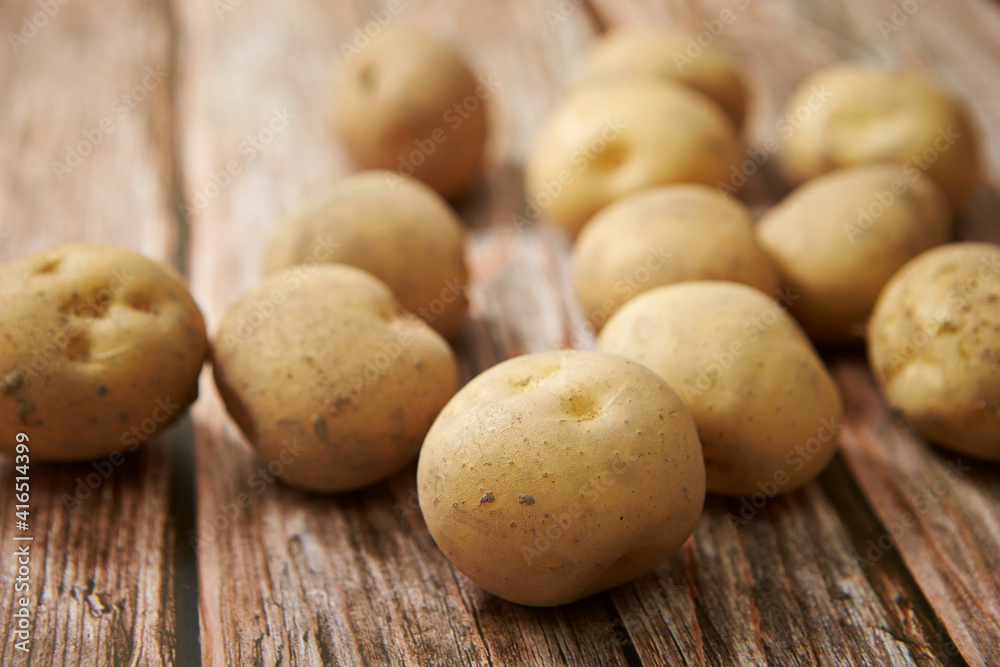 Fresh raw potatoes on a wooden background Fresh raw potatoes on a wooden background