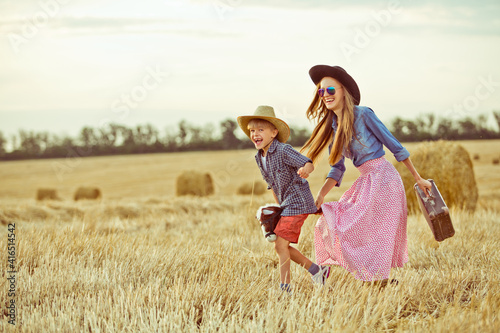 Mother and son having fun together on wtheat field wearing hats like cowboys