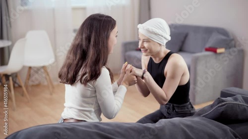 Young confident slim woman holding hands of friend and talking. Side view portrait of positive Caucasian lady cheering up supporting girlfriend at home indoors. Friendship and support.