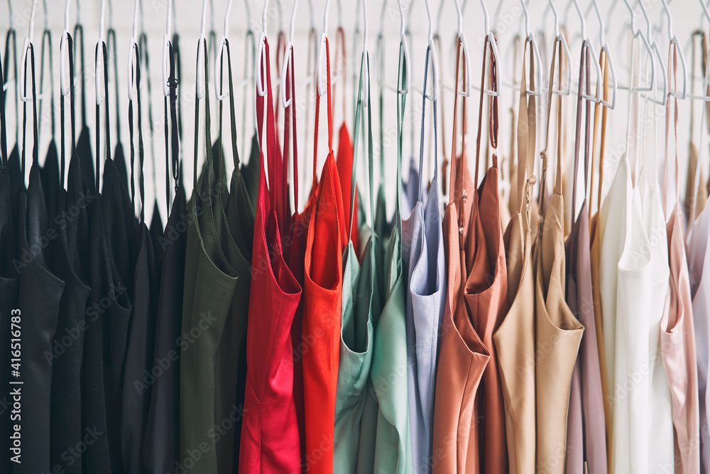 Multi-colored dresses hang on hangers in the store. Sale of women's dresses Multi-colored dresses hang on hangers in the store. Sale of women's dresses