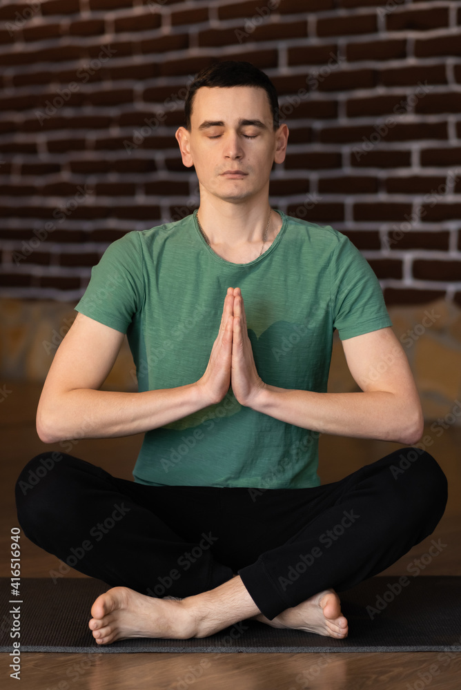 Handsome young man meditating in the living room Handsome young man meditating in the living room