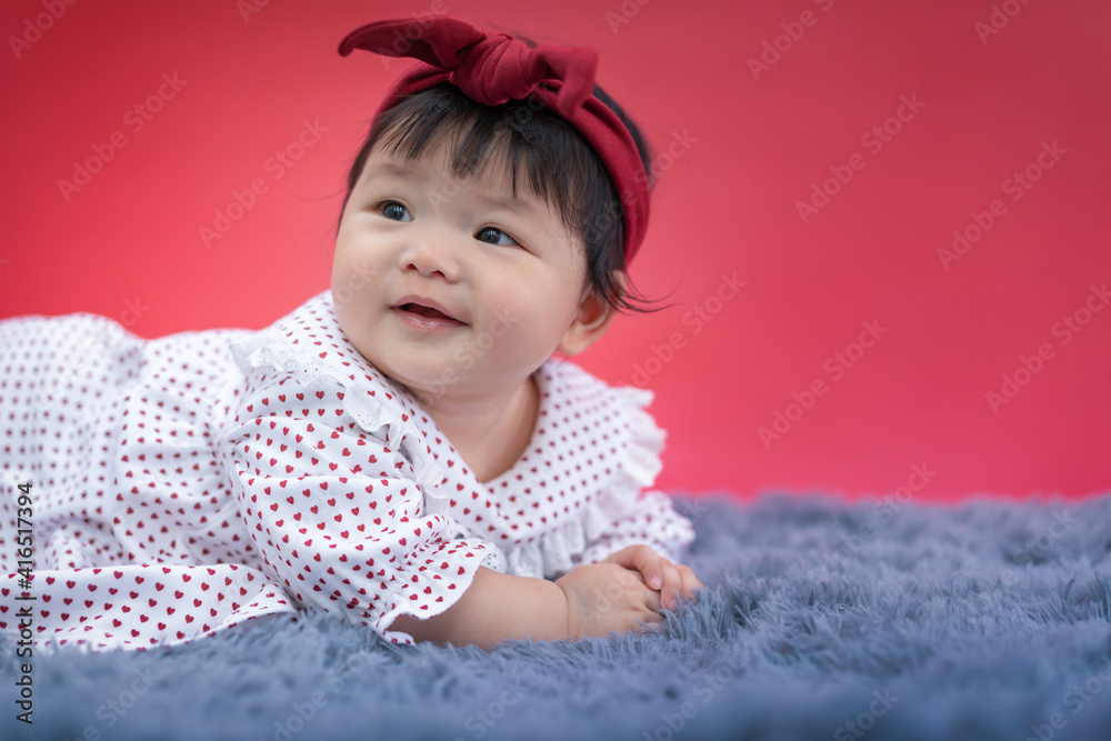 Asian happy baby crawling and smiling on carpet with red color background. Cute 6 months baby start crawling with copy space use as concept of valentine, love, baby or kid department in hospital. Asian happy baby crawling and smiling on carpet with red color background. Cute 6 months baby start crawling with copy space use as concept of valentine, love, baby or kid department in hospital.