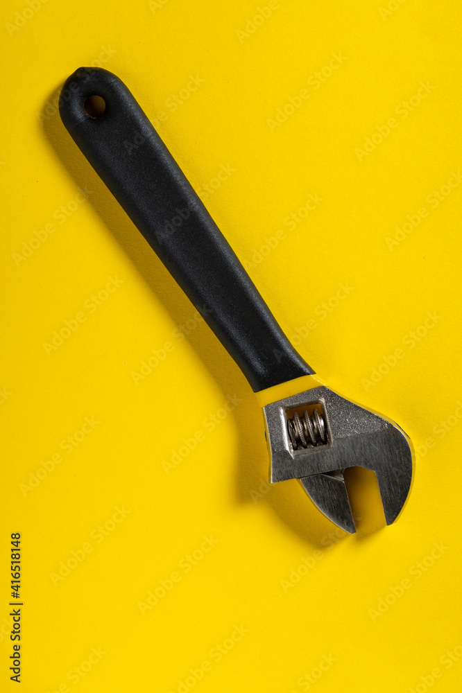 Adjustable wrench on a yellow background. Necessary tool of plumbing master or builder Adjustable wrench on a yellow background. Necessary tool of plumbing master or builder