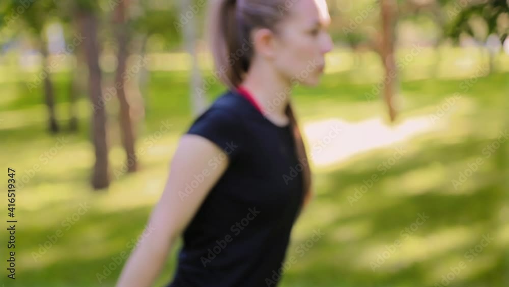 Follow focus from bokeh to slim, athletic woman doing exercise with dumbbells. Fitness in a summer park. Follow focus from bokeh to slim, athletic woman doing exercise with dumbbells. Fitness in a summer park.