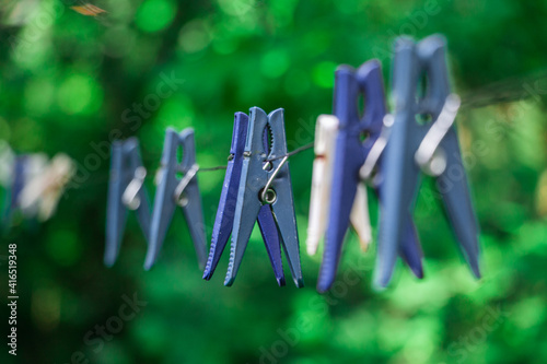 clothespins hanging with wire on​ green​ blur​ background. Old clothespins hang on the wire outdoor, blurred background, selective focus.colorful clothespins hang on a wire 