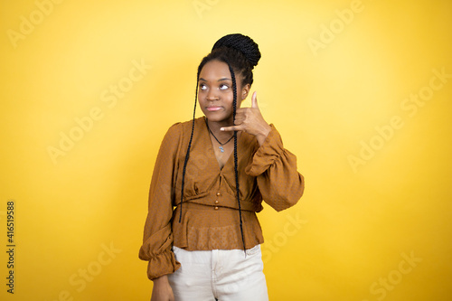 African american woman wearing casual clothes smiling doing phone gesture with hand and fingers like talking on the telephone © Irene