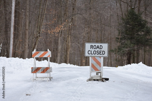 Road closed sign and barricade warning of dangerour snow and ice covered mountain road photo