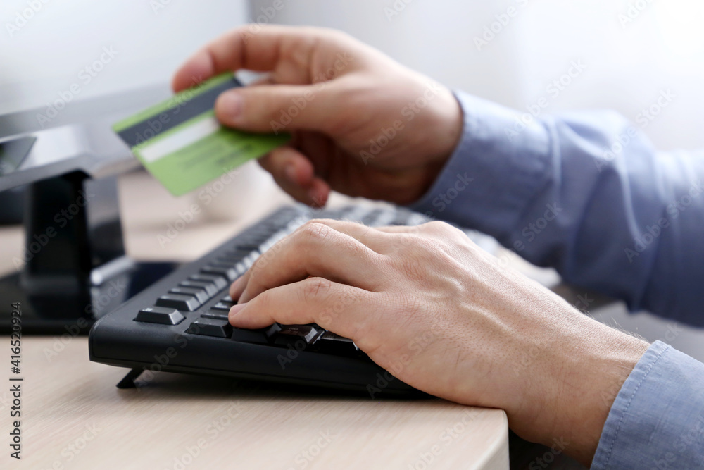 Man holding credit bank card types on PC keyboard. Concept of online shopping and payment, financial transactions