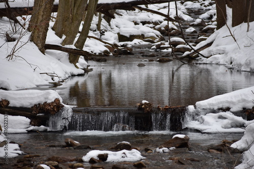 Mountain stream with small waterfall in winter with snow and ice covered bank in Western Pennsylvania