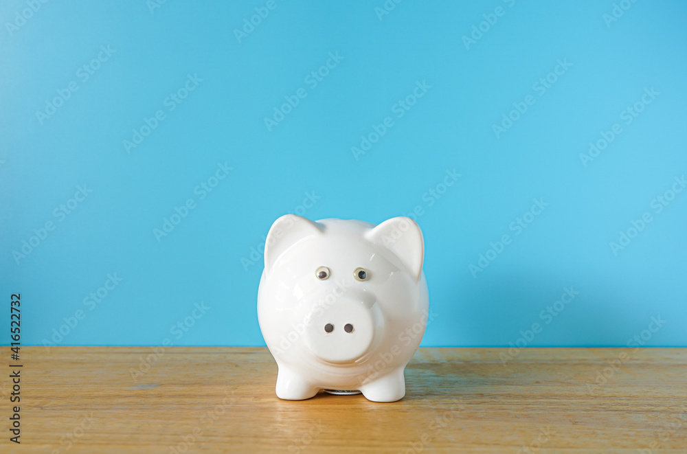 White Piggy bank on blue background with copy space White Piggy bank on blue background with copy space