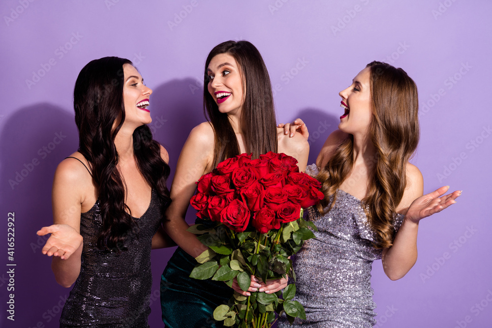 Photo of three funny ladies hold roses share rumors laugh wear glossy dresses isolated purple color background Photo of three funny ladies hold roses share rumors laugh wear glossy dresses isolated purple color background