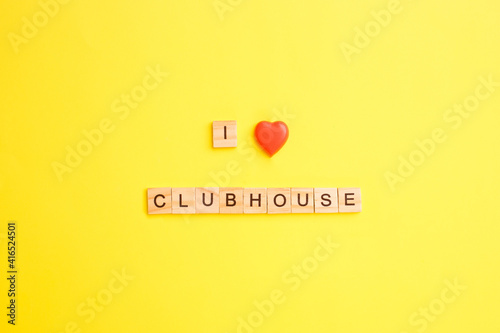 Wooden blocks with letters form the words I love clubhouse on a yellow background.