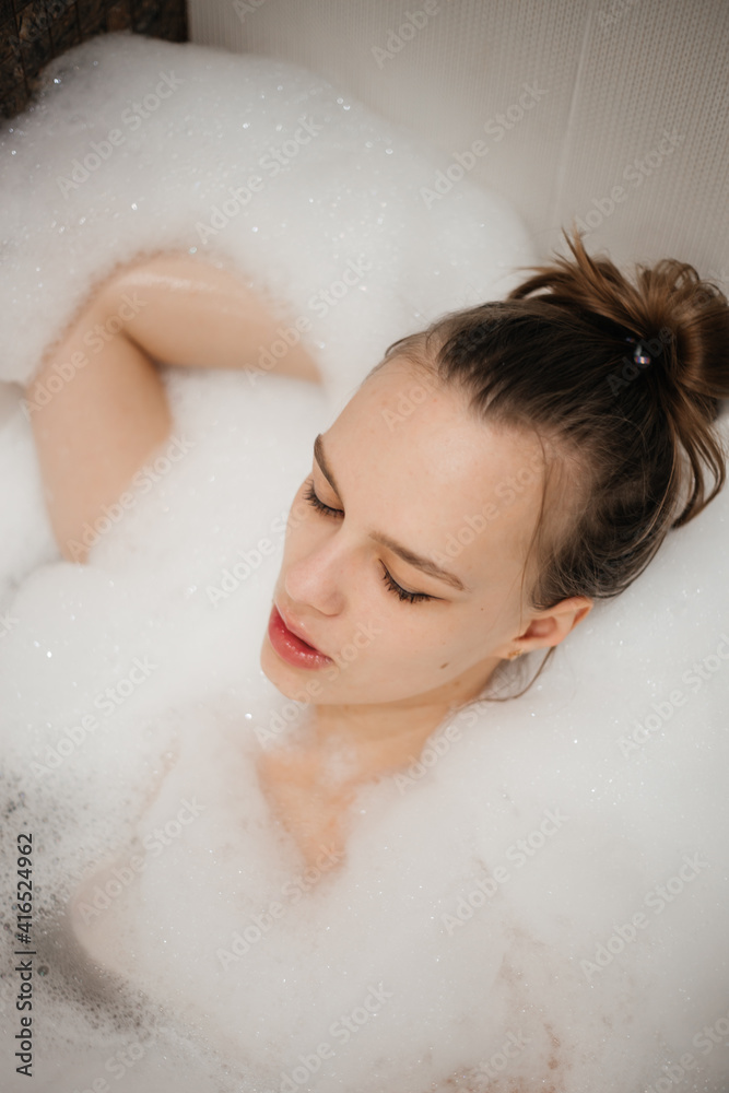 The girl takes a bath all in foam. Beautiful portrait. Spa treatments and relaxation