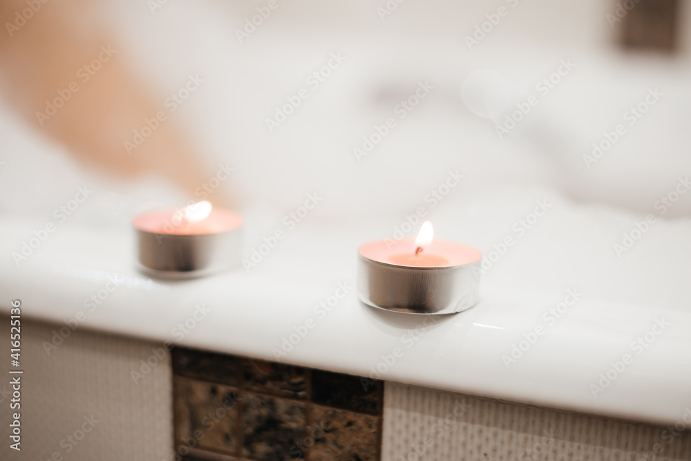 Two pink scented candles. Atmosphere of relaxation and tranquility, pleasure. Girl in foam takes a bath on the background. Two pink scented candles. Atmosphere of relaxation and tranquility, pleasure. Girl in foam takes a bath on the background.