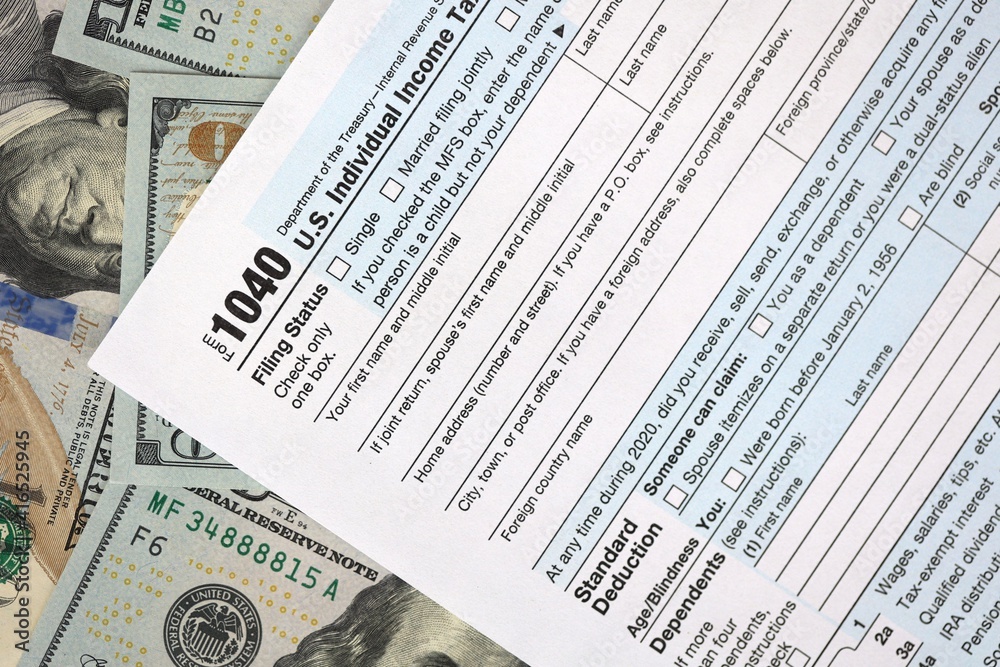 One hundred dollar bills and US 1040 tax form. Calculating your tax ...