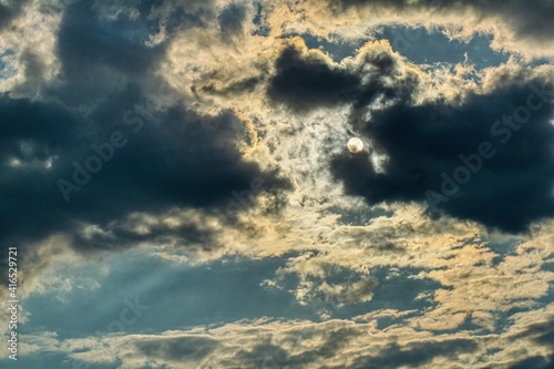 Słońce przebijające się przez chmury dramatyczne niebo niepewna aura pogody wiatry rozganiające chmury