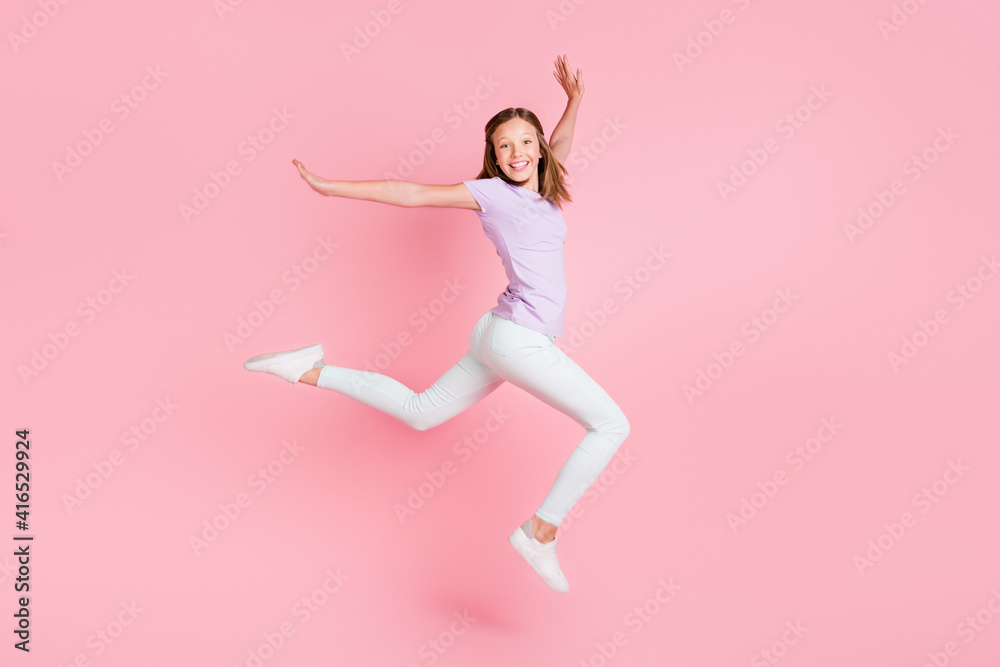 Full body profile side photo of happy cheerful small girl jump up raise hands isolated on pink color background