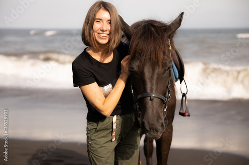 Portrait of smiling woman and brown horse. Young Caucasian woman hugging horse. Romantic concept. Love to animals. Nature concept. Bali © Olga