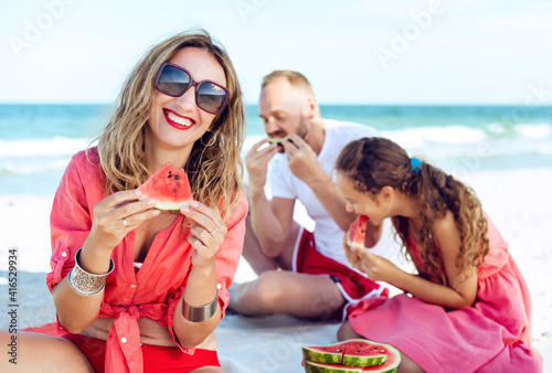Smiling family are quenching their thirst and eating watermelon